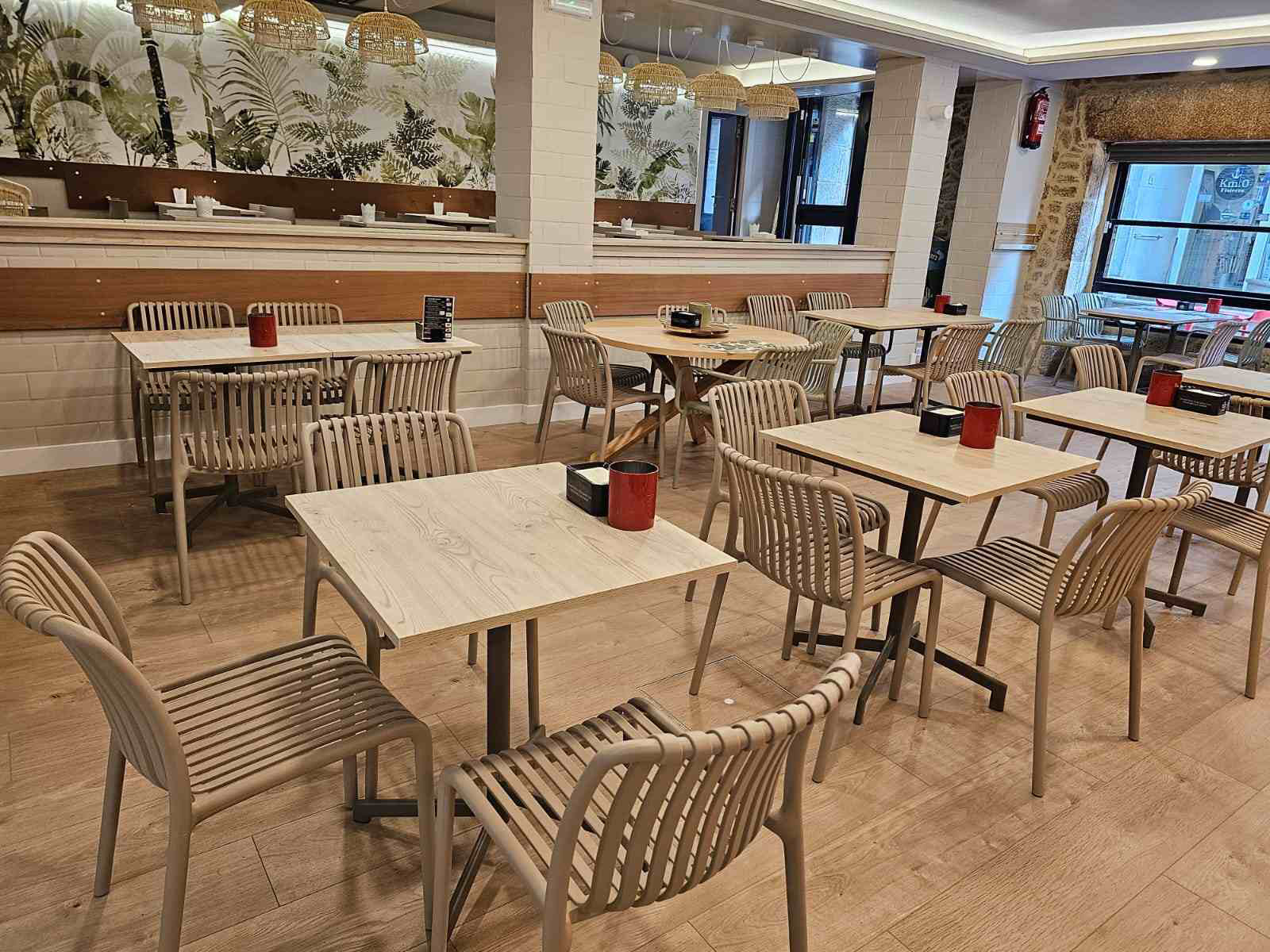 elegante cagetería con sillas y mesas de color beige con la barra al fondo de color marrón, instalaciones nuevas y muy limpias